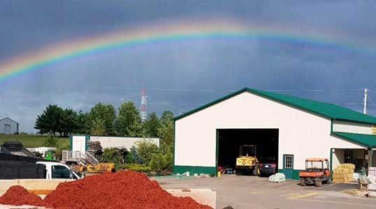 A white building with a green roof and a rainbow in the sky.