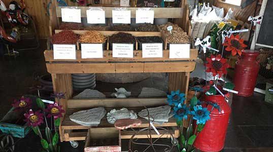 A wooden shelf filled with different types of food and flowers.