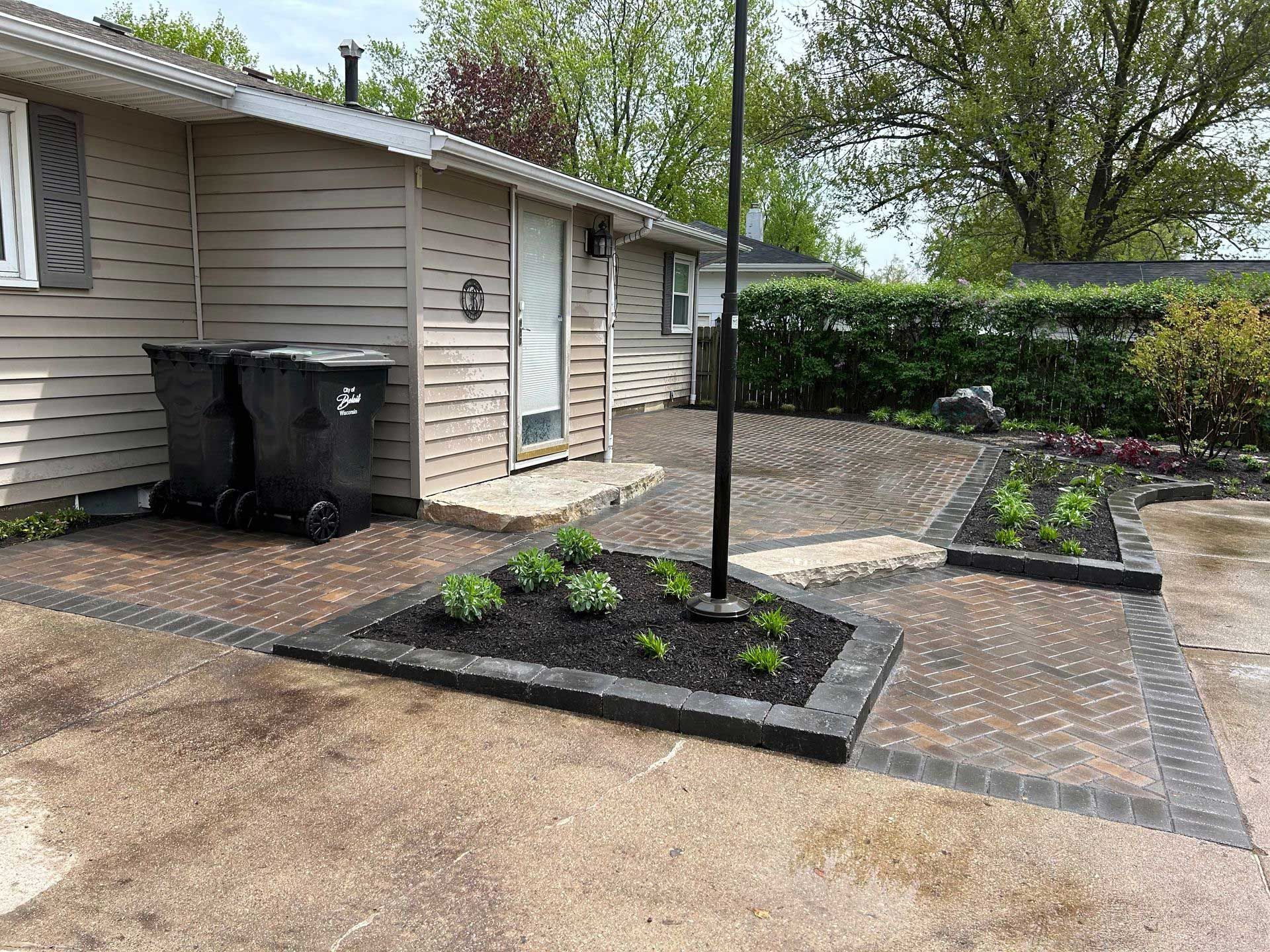 A house with a patio and trash cans in front of it.