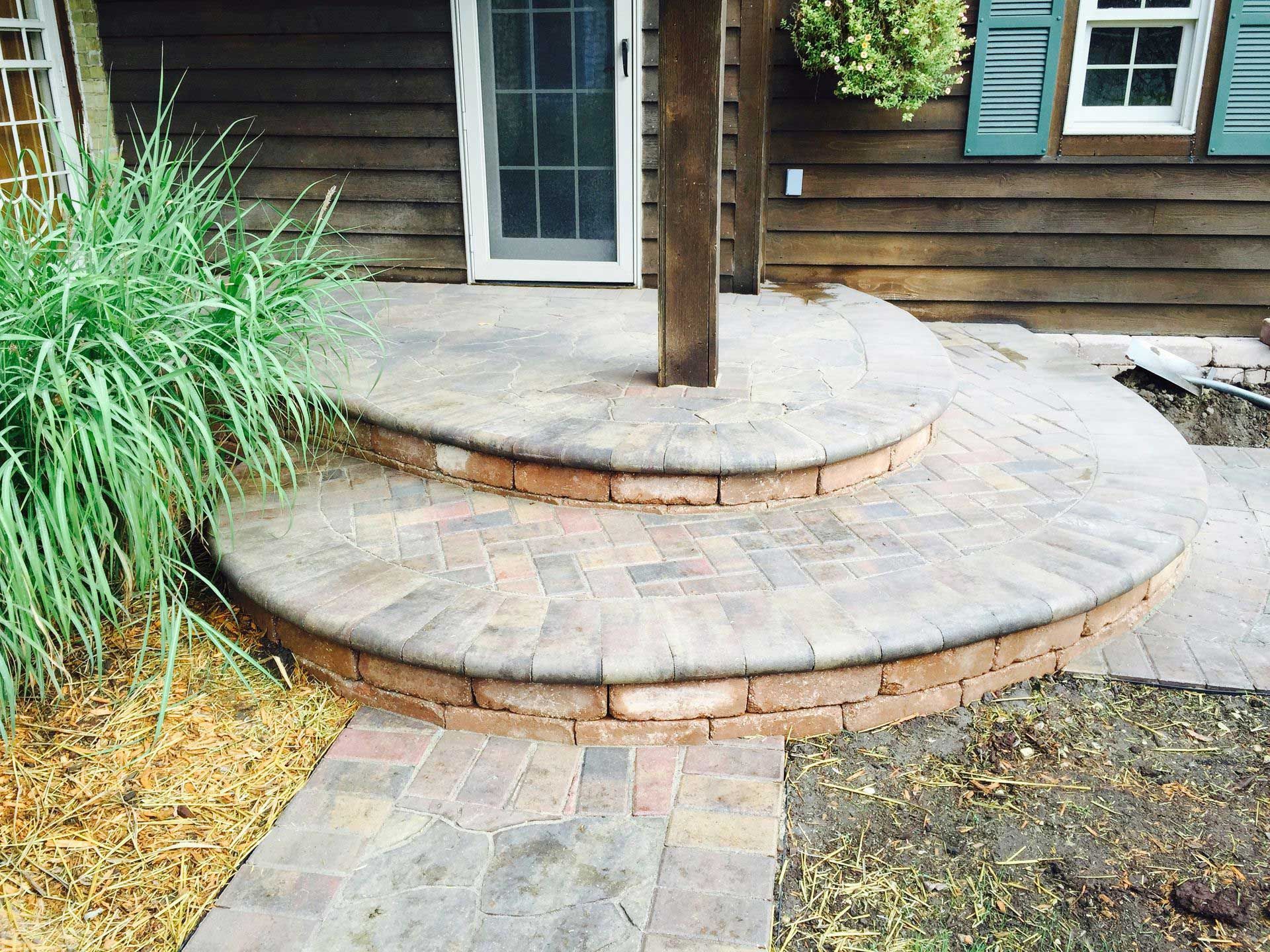 A brick walkway leading to a porch with steps