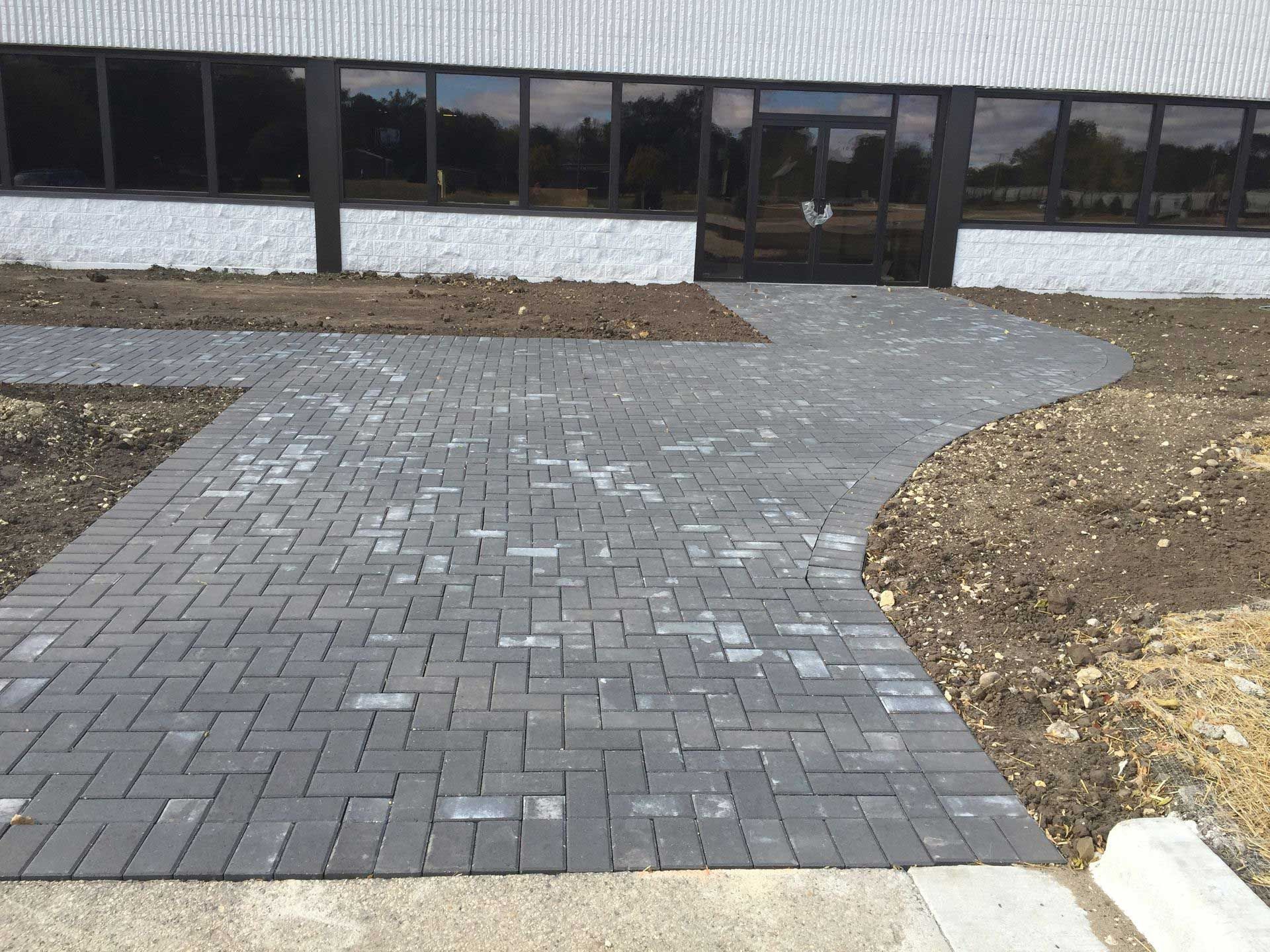 A brick walkway leads to a building with lots of windows