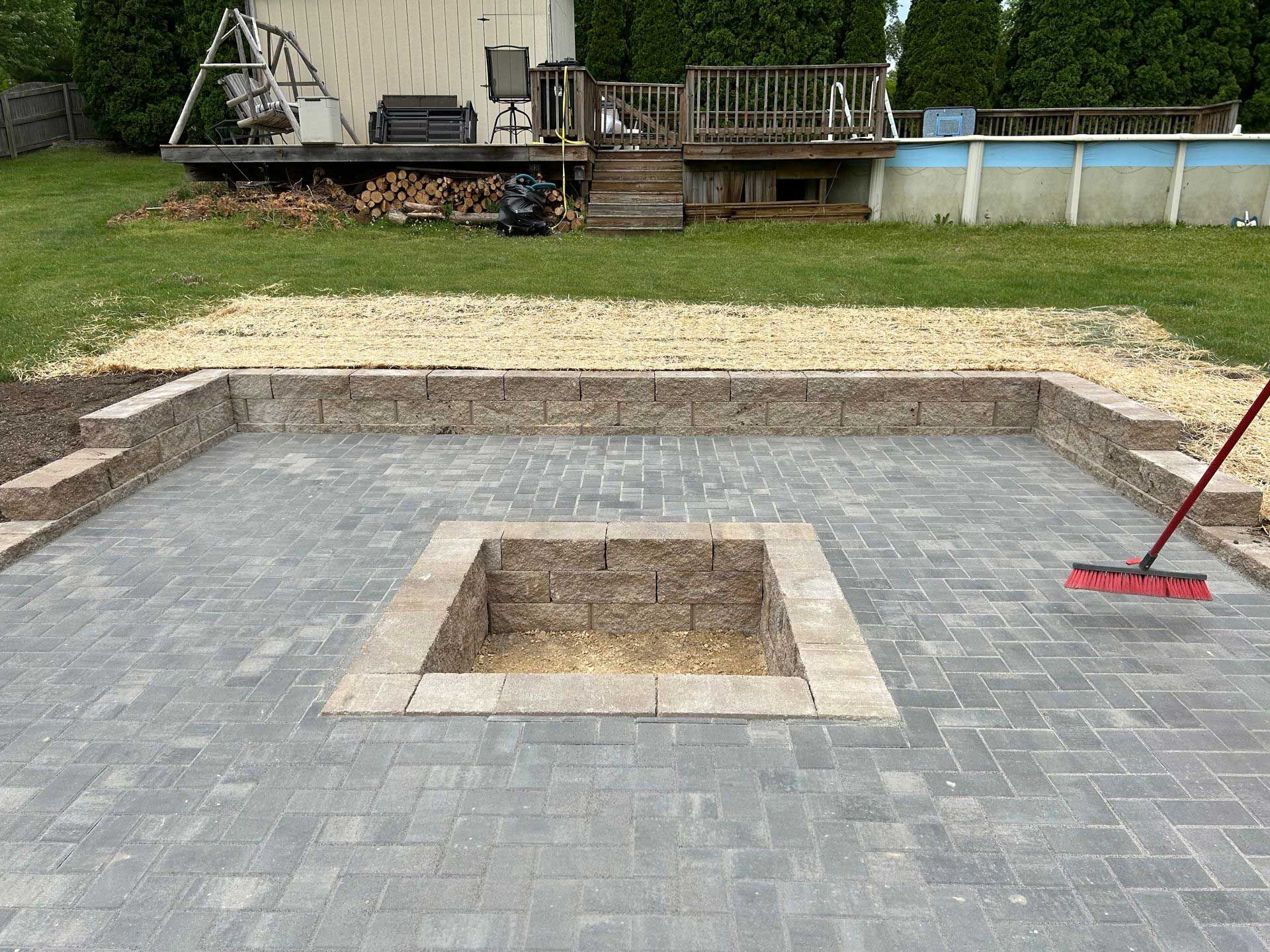 A fire pit is being built in a backyard next to a pool.