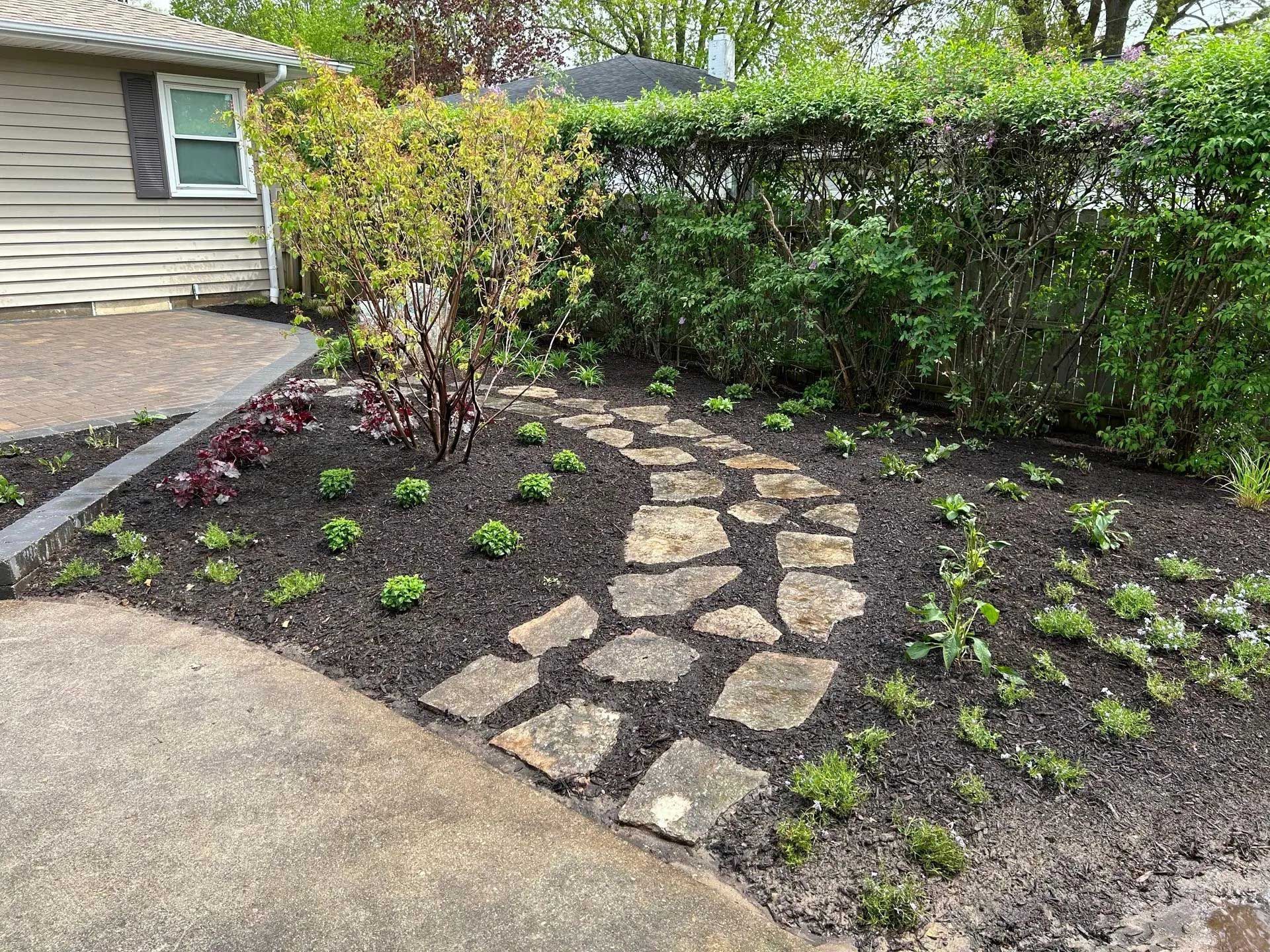 A stone walkway in a garden next to a house.