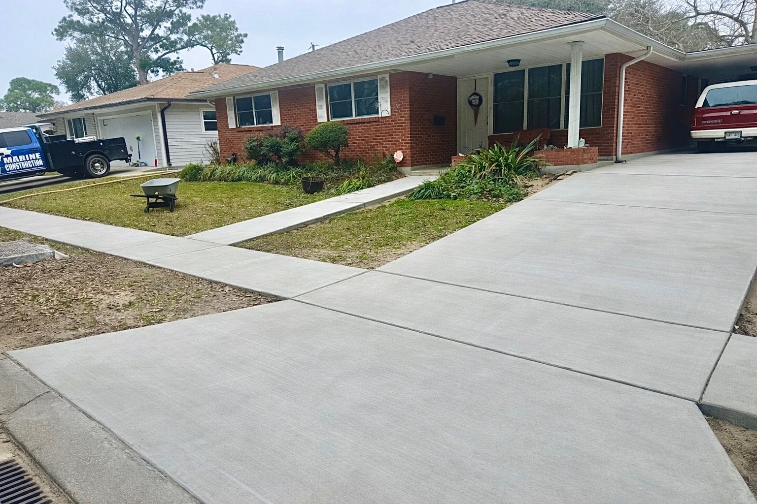 Suburban house with red brick facade, driveway, and attached carport; a truck parked nearby.