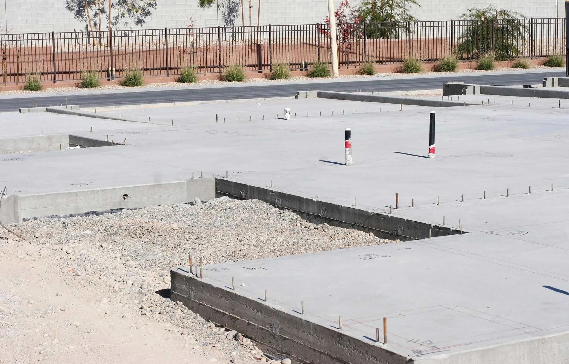 Concrete foundation with gravel and piping. Construction site.