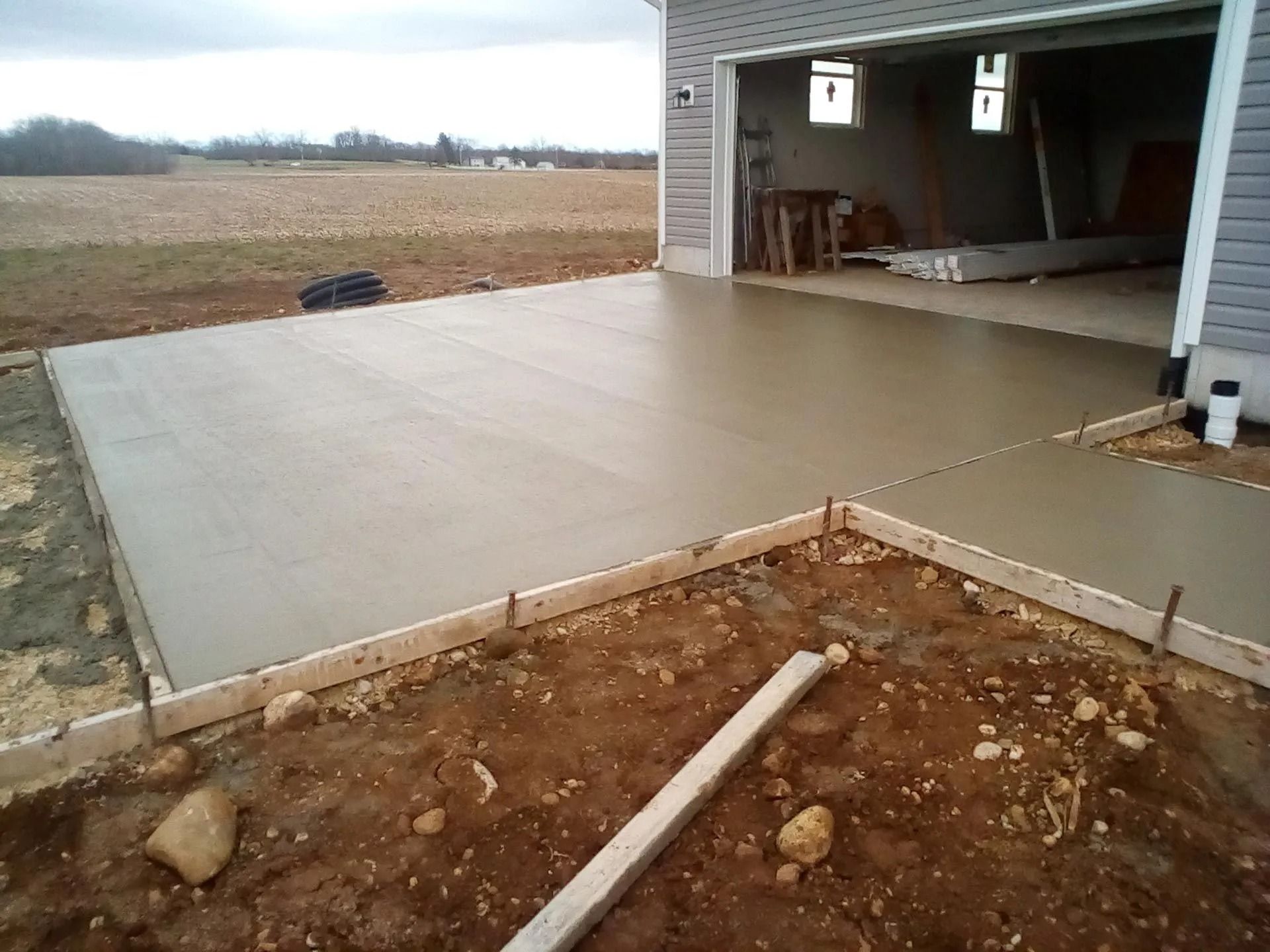 Freshly poured concrete driveway and walkway outside a garage.