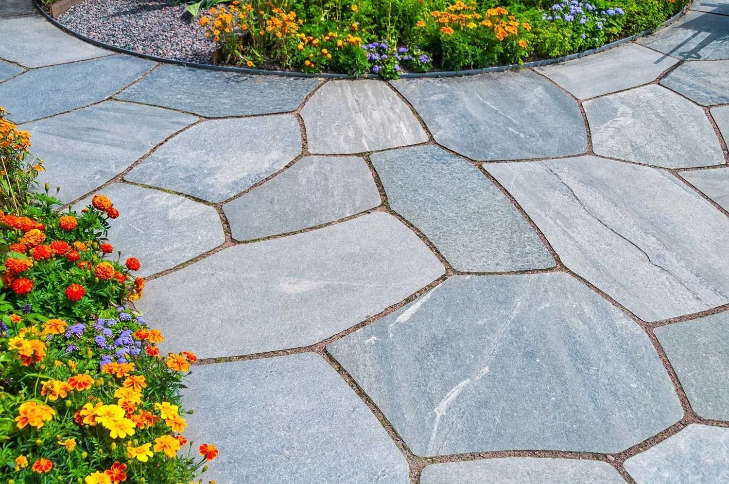 Stone walkway with irregular shapes, surrounded by colorful flowers.