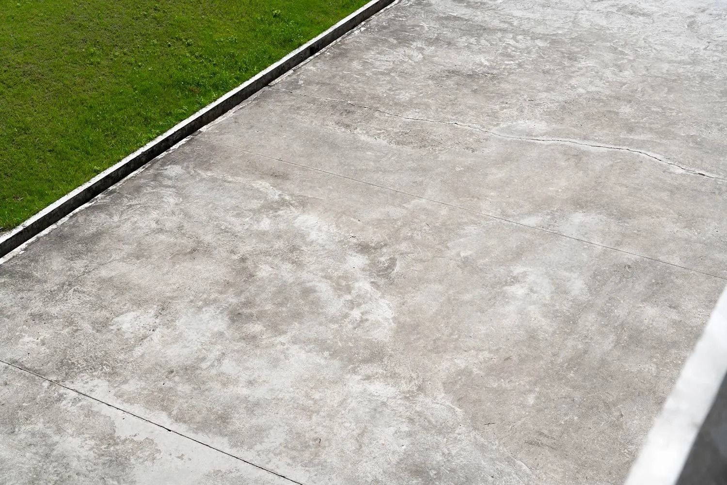 Concrete ground next to a patch of green grass.