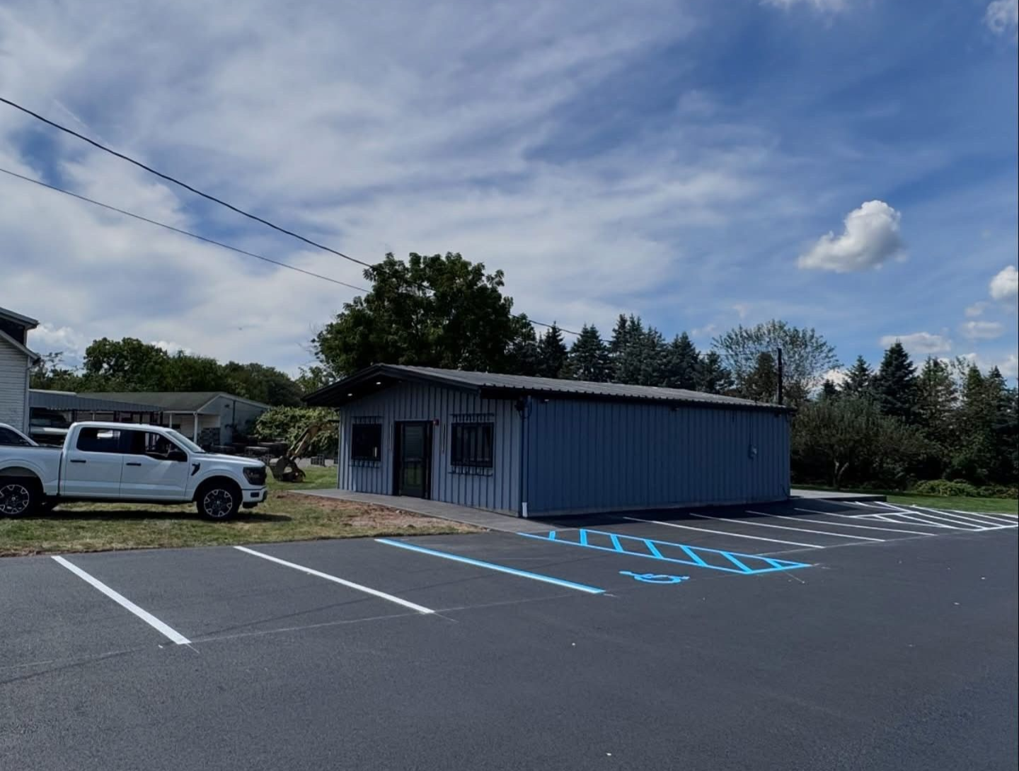 Blue building with parking spots, white truck, and blue sky.