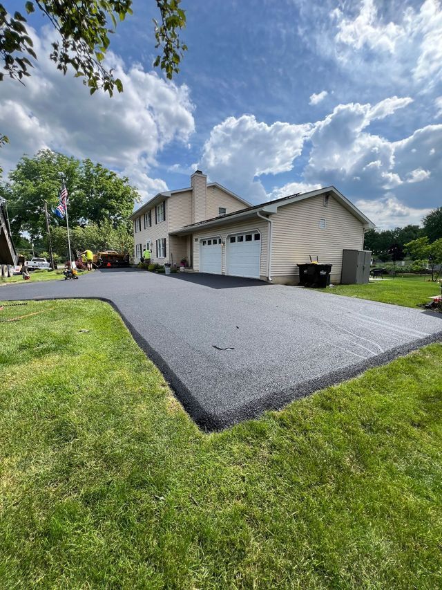 A house with a driveway that is being paved in front of it.