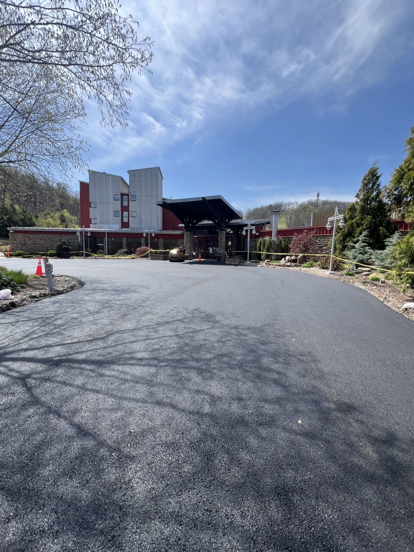 Wide gravel driveway leading to a building entrance with a canopy, under a bright blue sky