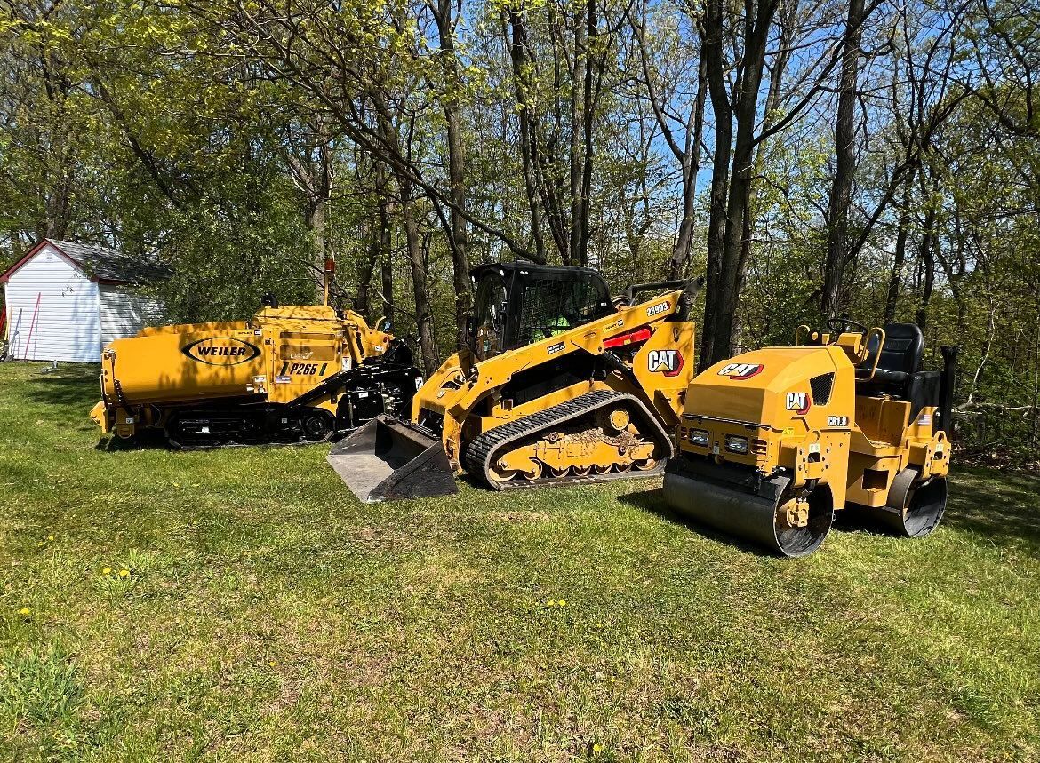 A couple of yellow tractors are parked in a grassy field.