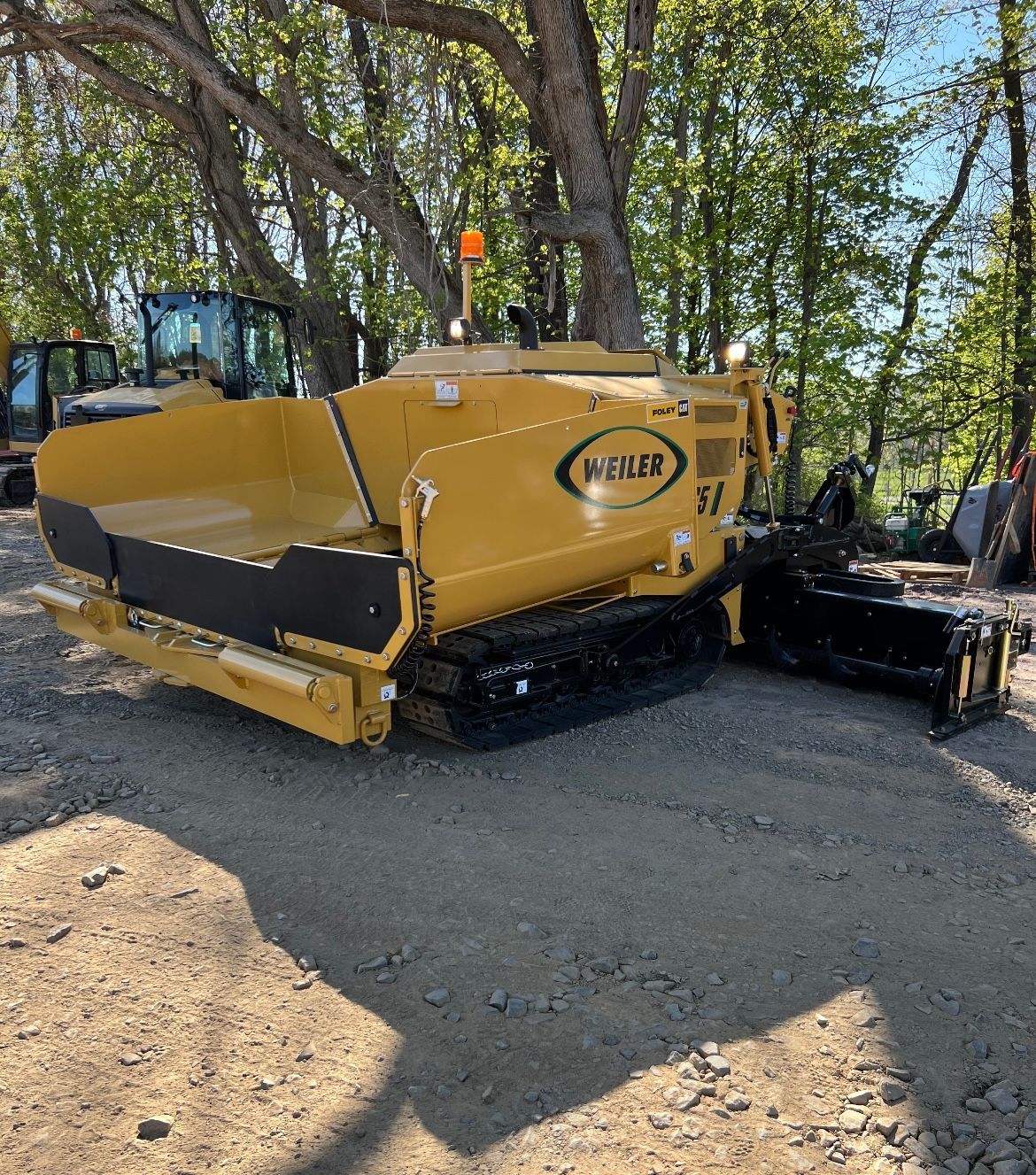 A yellow and black tractor is parked on a dirt road.