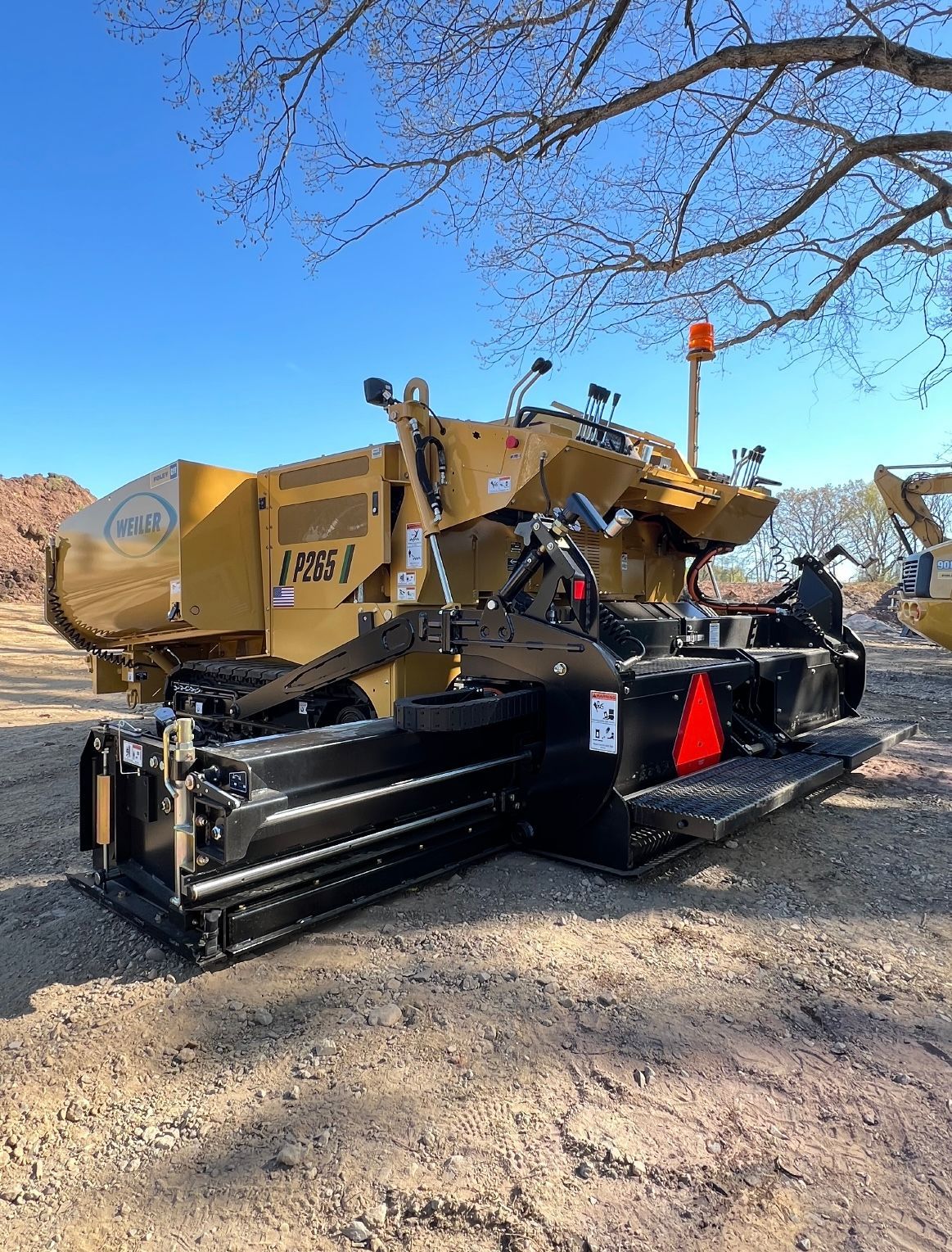 A large yellow and black machine is parked in a dirt field.