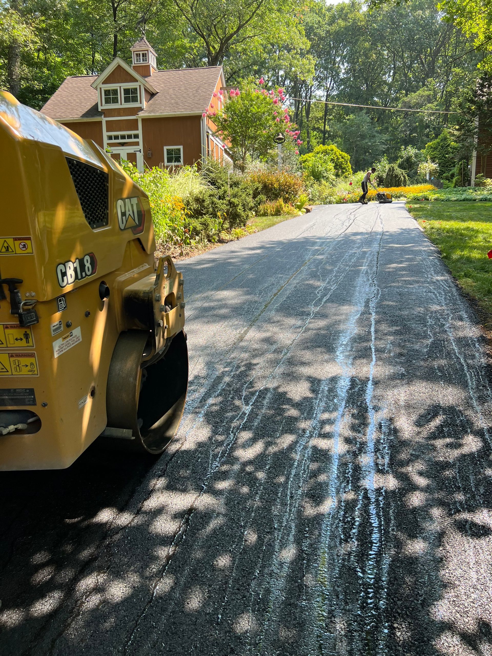 A yellow roller is driving down a road next to a house.