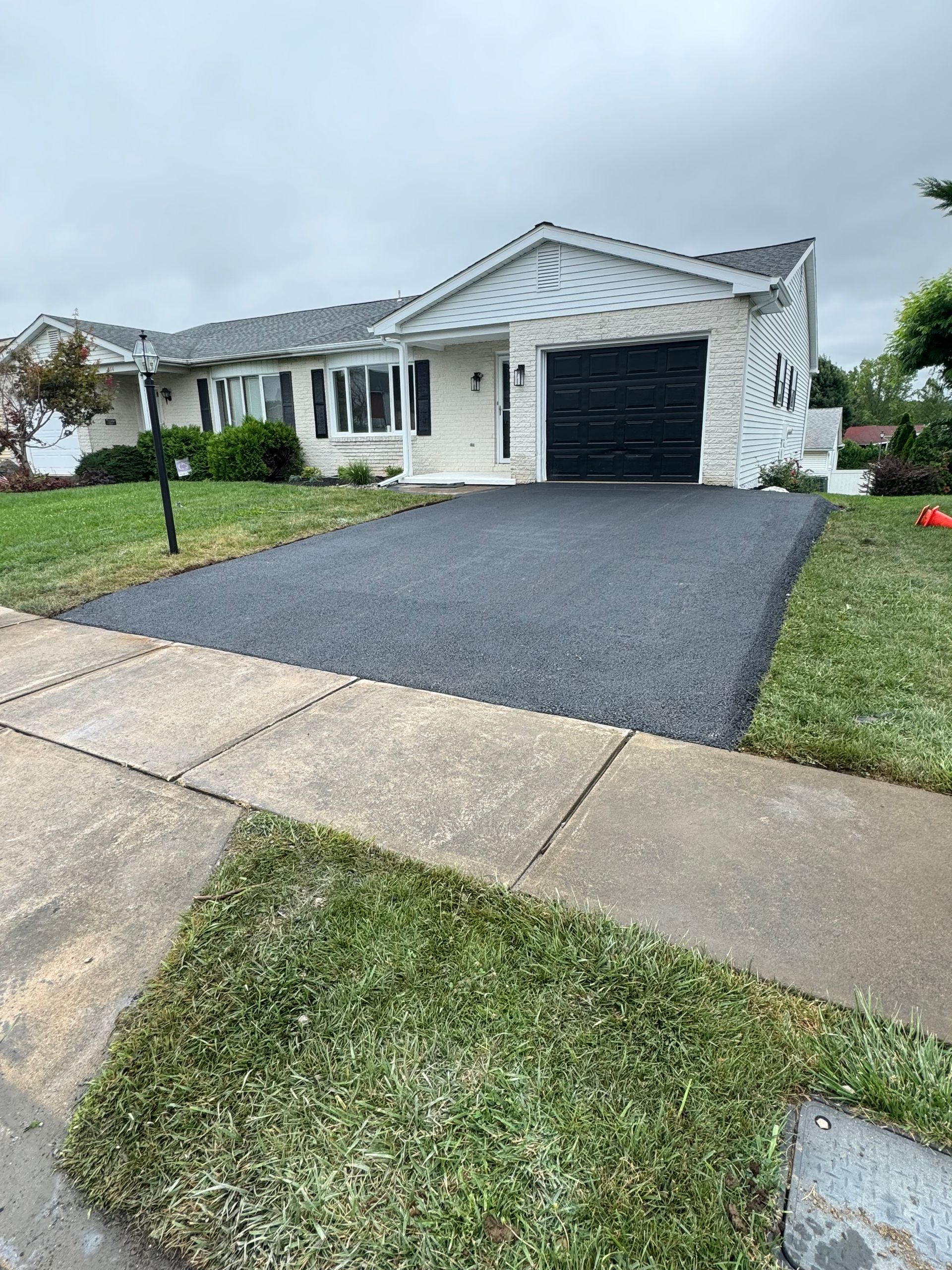 A white house with a black garage door and a black driveway.