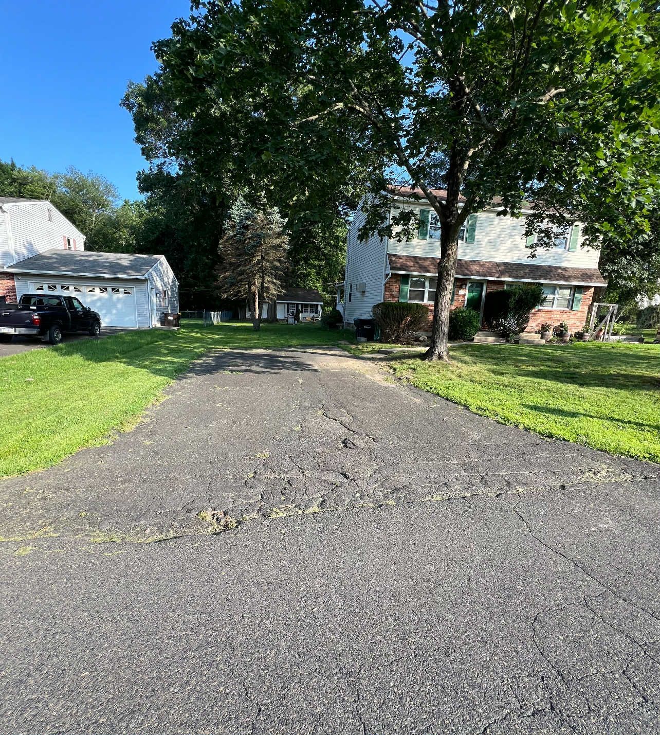 A driveway leading to a house with a car parked in front of it.