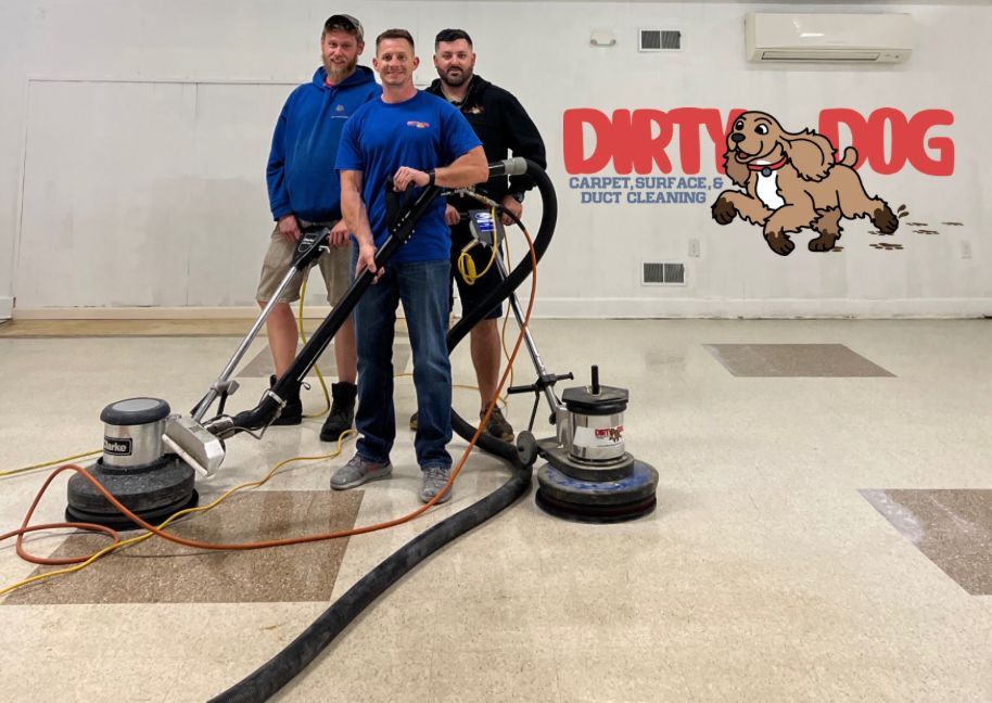 Three men with carpet cleaning machines in front of a Dirty Dog logo, on a cleaned beige carpet.