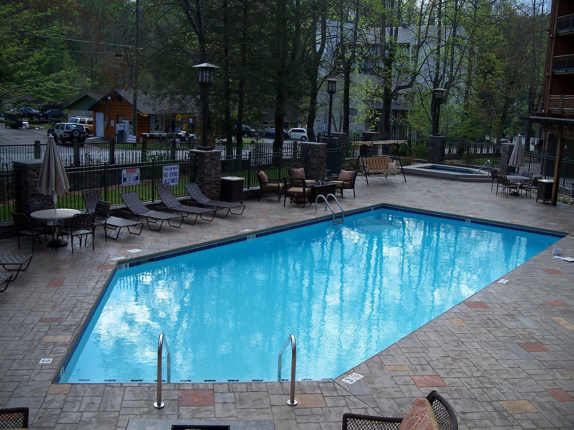 Outdoor swimming pool surrounded by trees and lounge chairs in a wooded resort setting