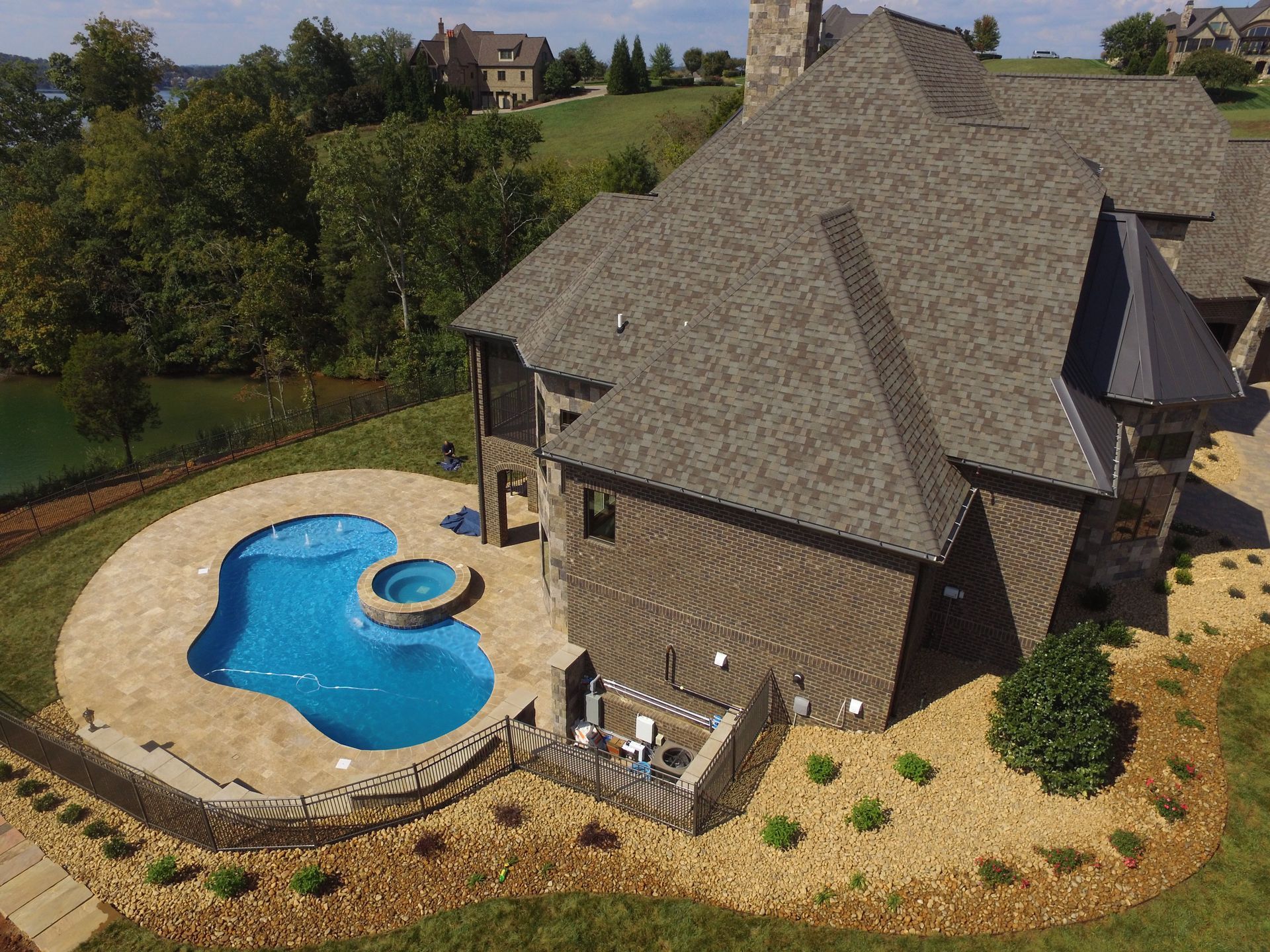 Aerial view of a house with a curved blue swimming pool and landscaped yard