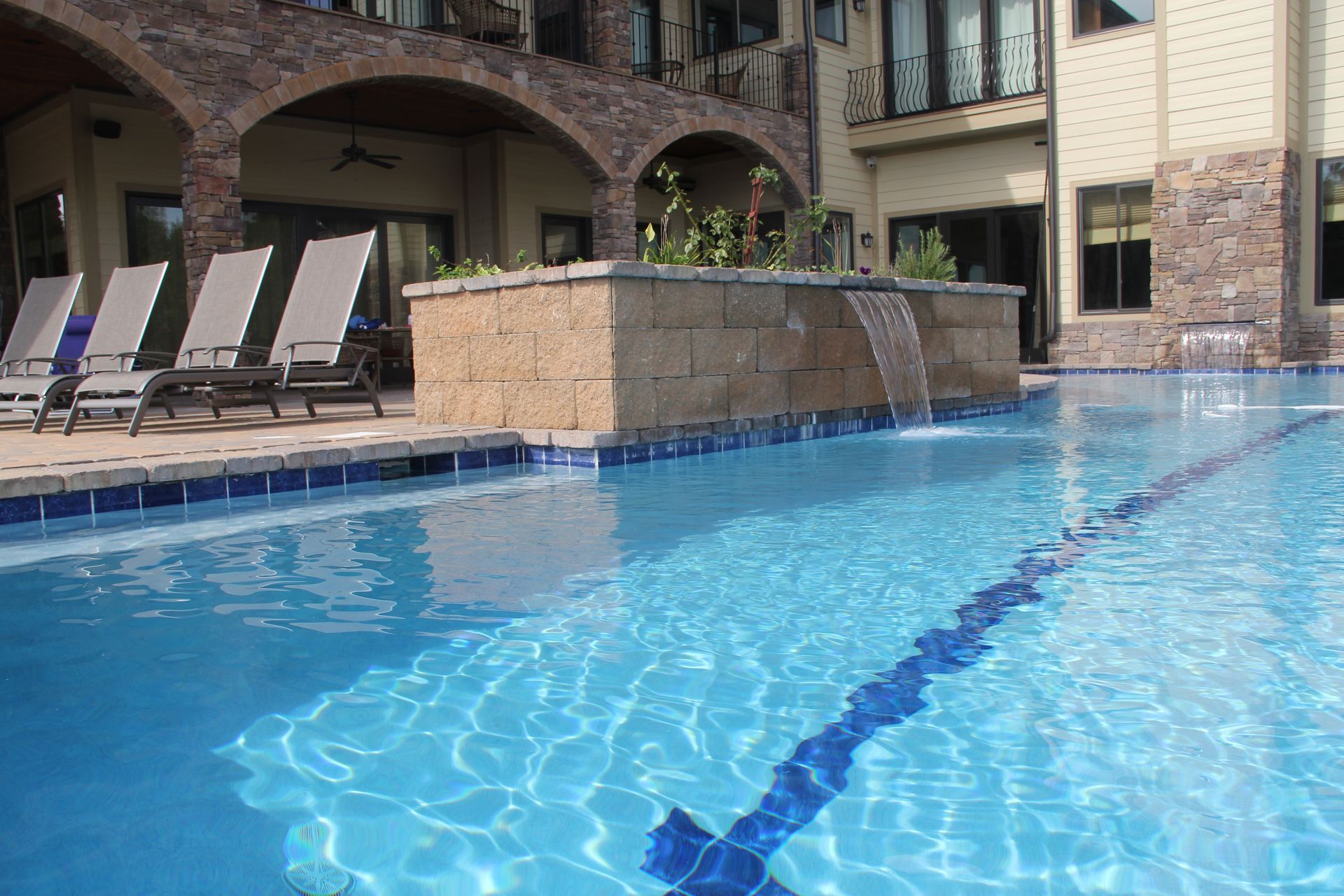 Outdoor hotel pool with blue water, lounge chairs, and brick building courtyard