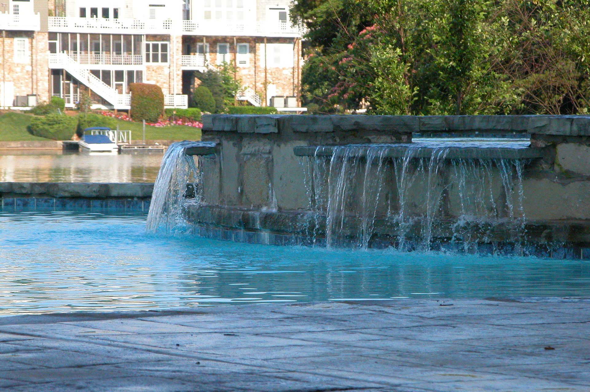 Water fountain spilling into a blue pool with a building in the background
