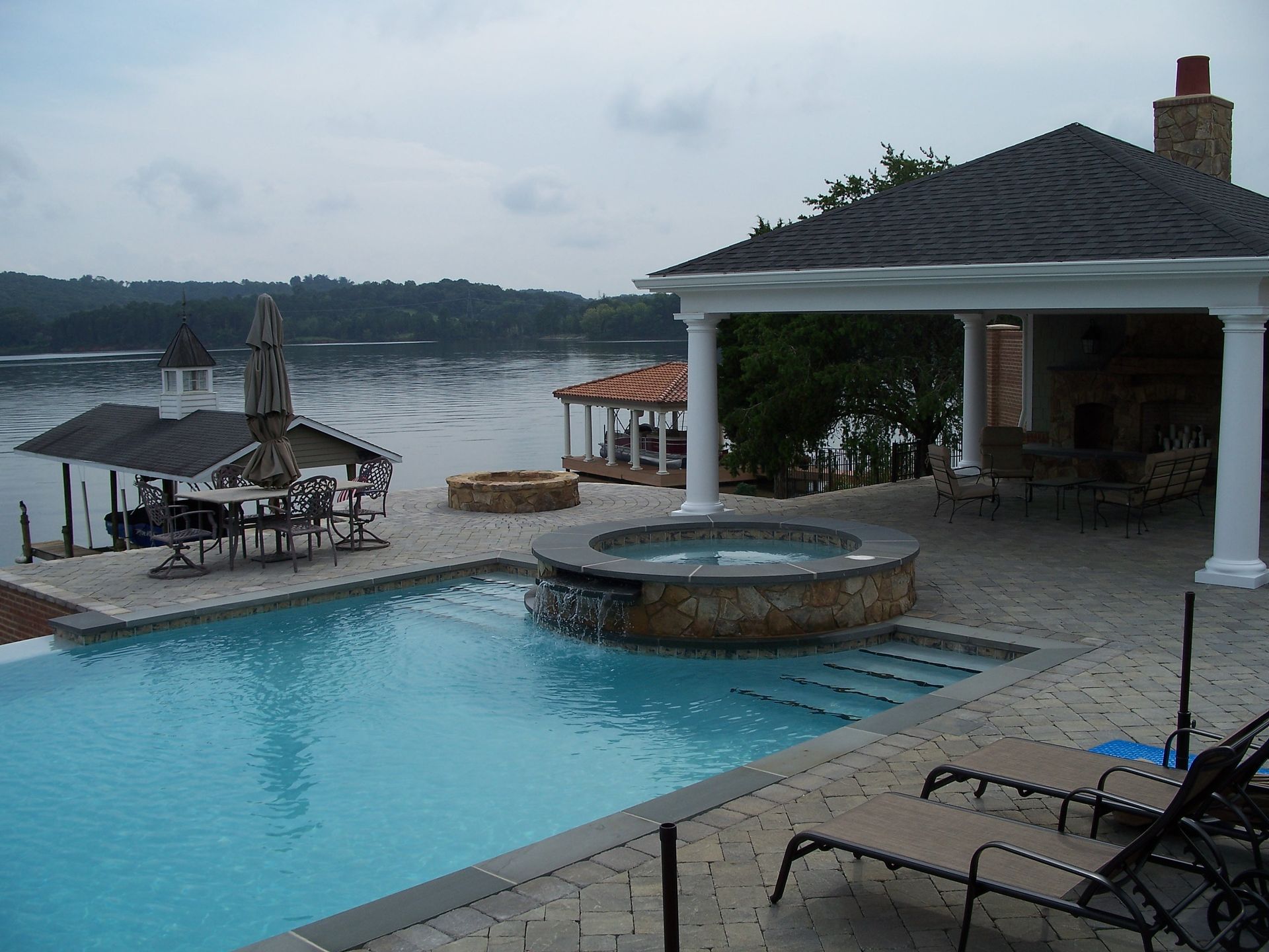 Oceanfront resort pool beside a thatched bar and white gazebo at dusk