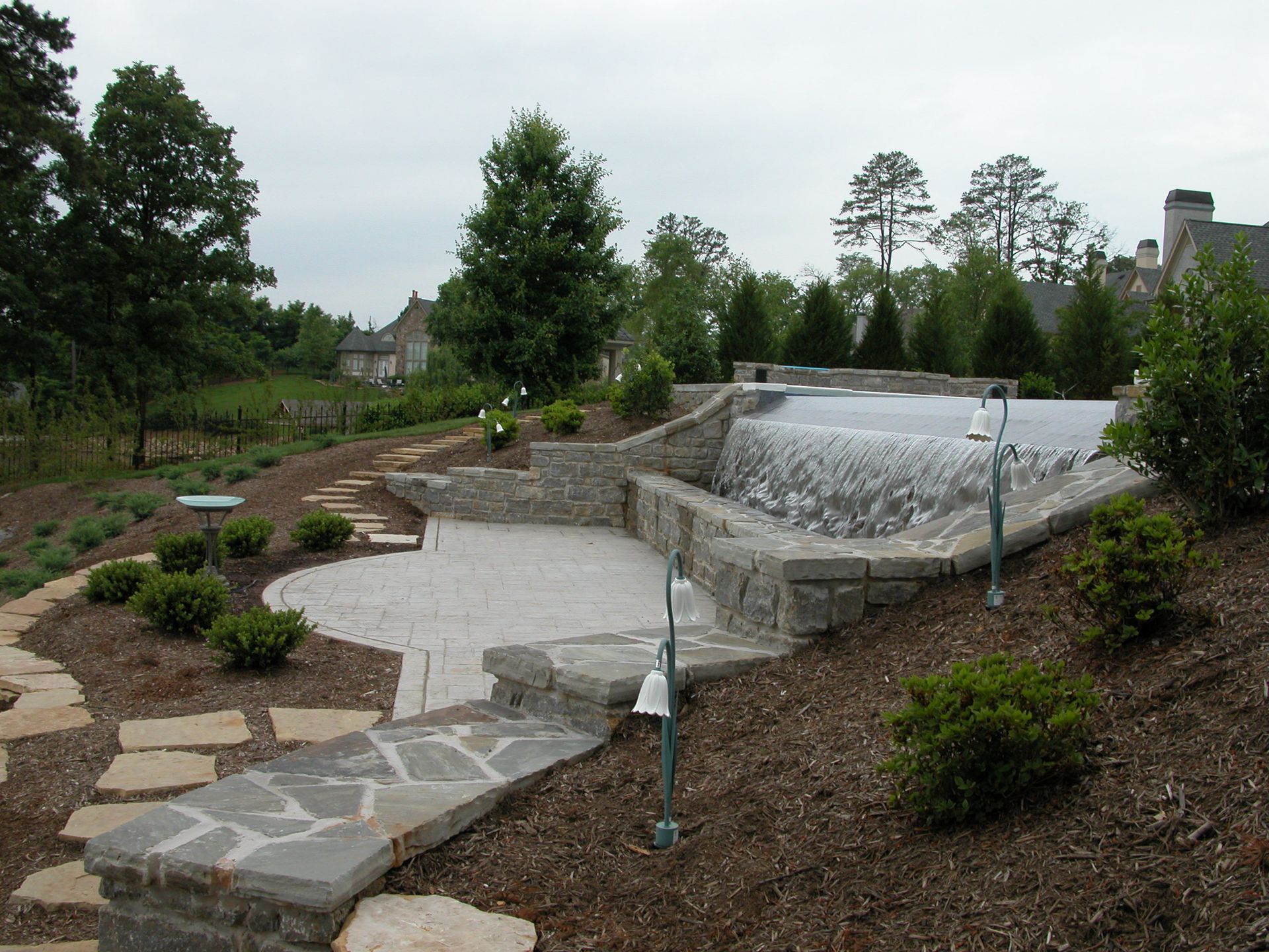 Stone pathway and landscaped garden with a tiered water feature and small waterfall