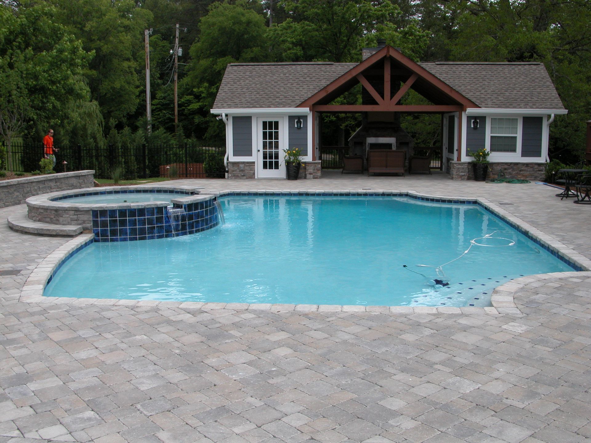 Backyard pool with a stone deck and a small cabana in the background
