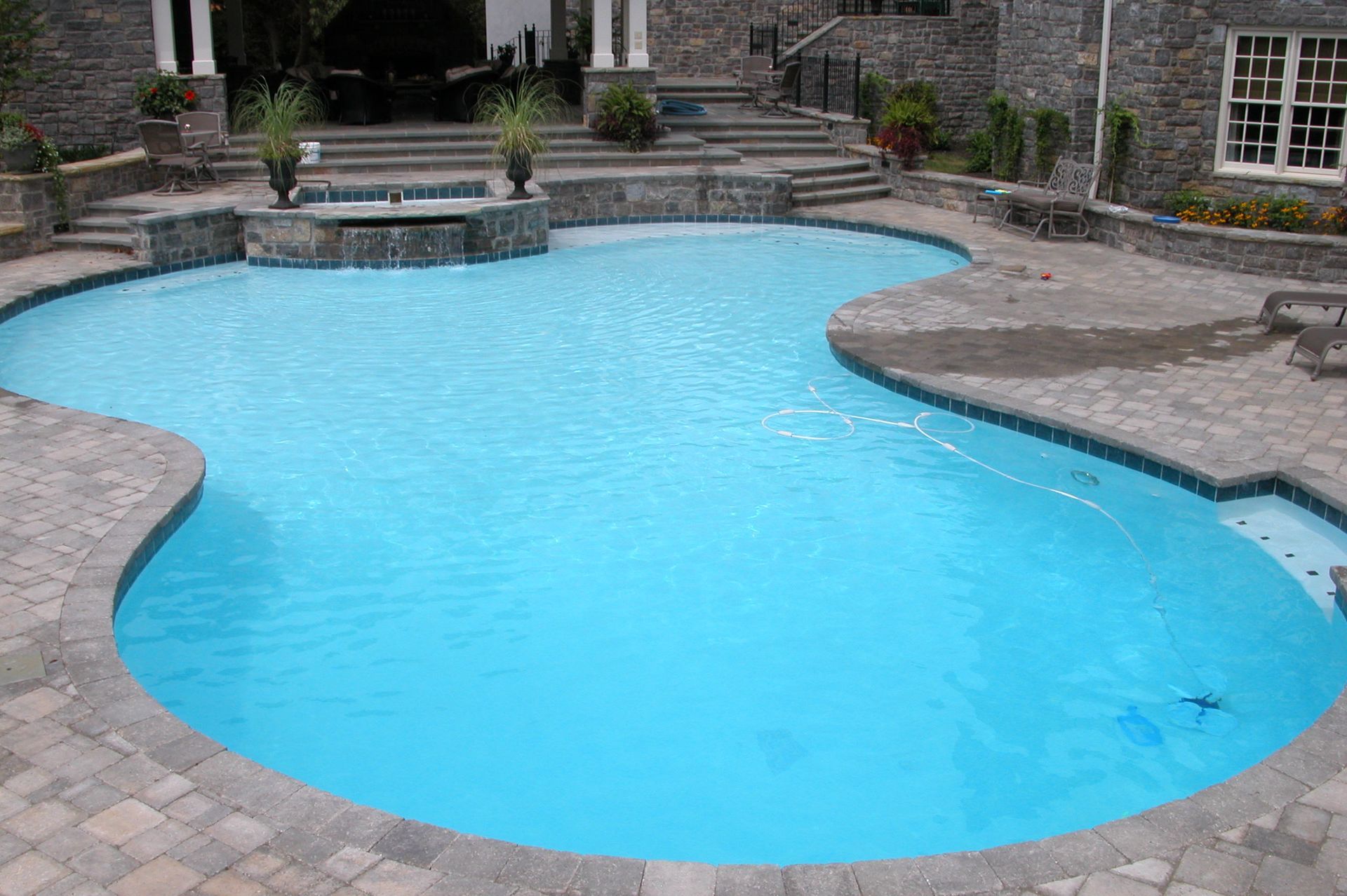 Backyard swimming pool with bright blue water and stone patio surroundings