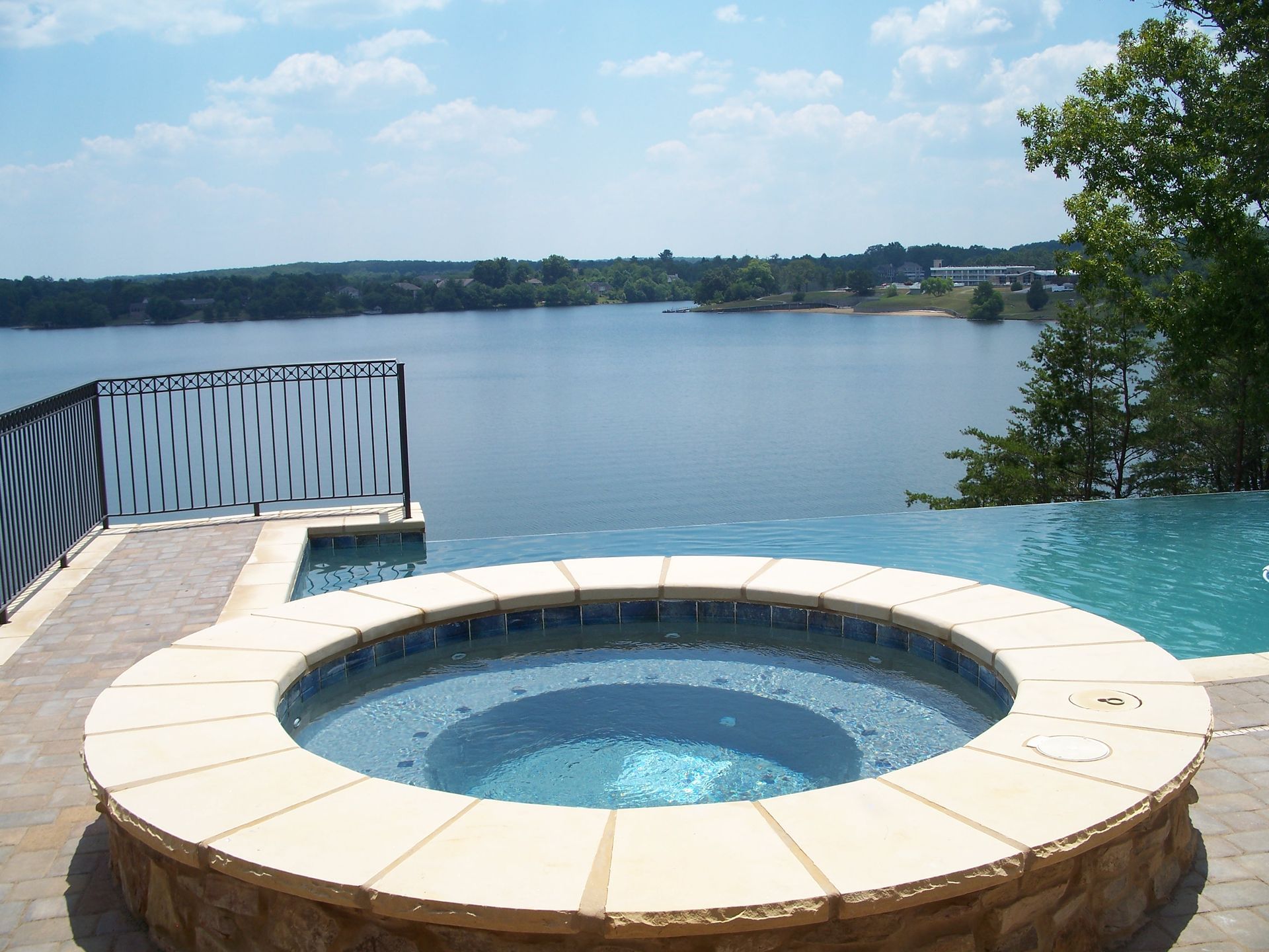 Circular hot tub on a deck overlooking a calm lake under a blue sky