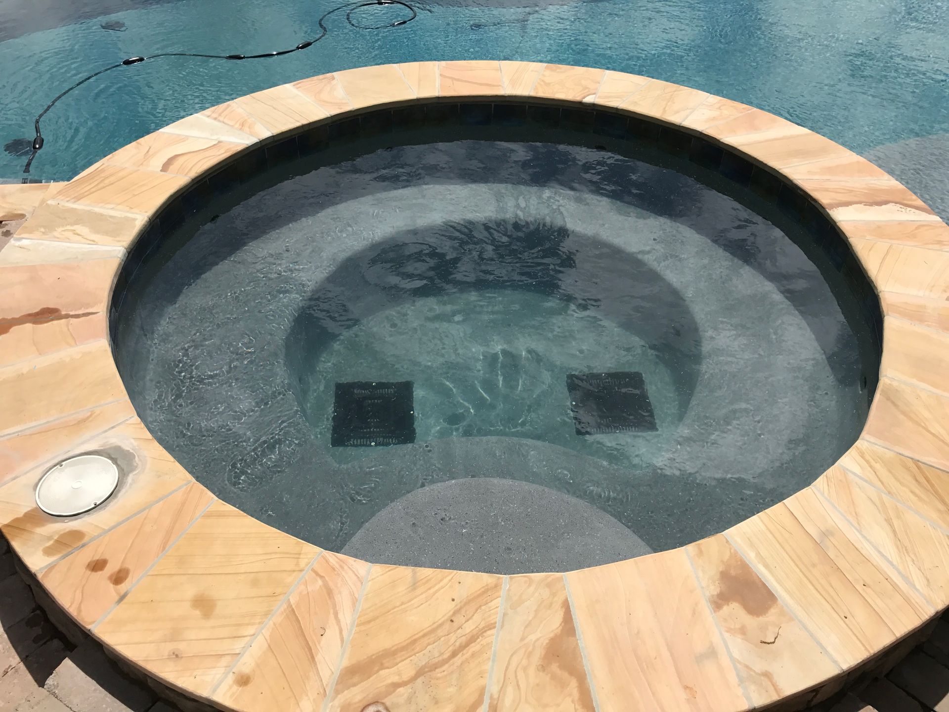 Circular hot tub with wood-look deck surround and clear water, viewed from above