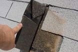 A person is holding a piece of brick on top of a roof.
