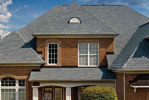 A large brick house with a gray roof and white windows.