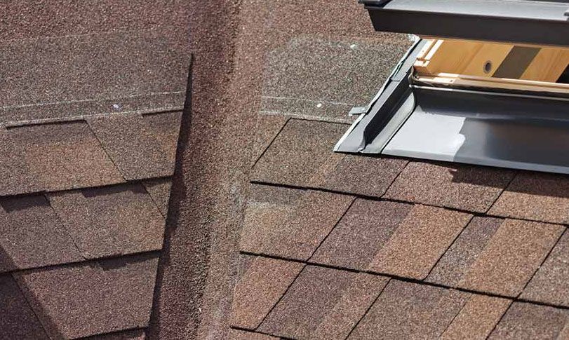 A roof with shingles and a skylight on it