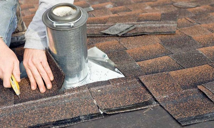 A man is installing a chimney on a roof.