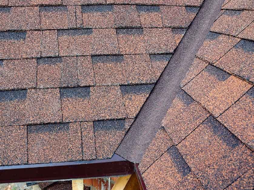 A close up of a roof with shingles and a gutter.