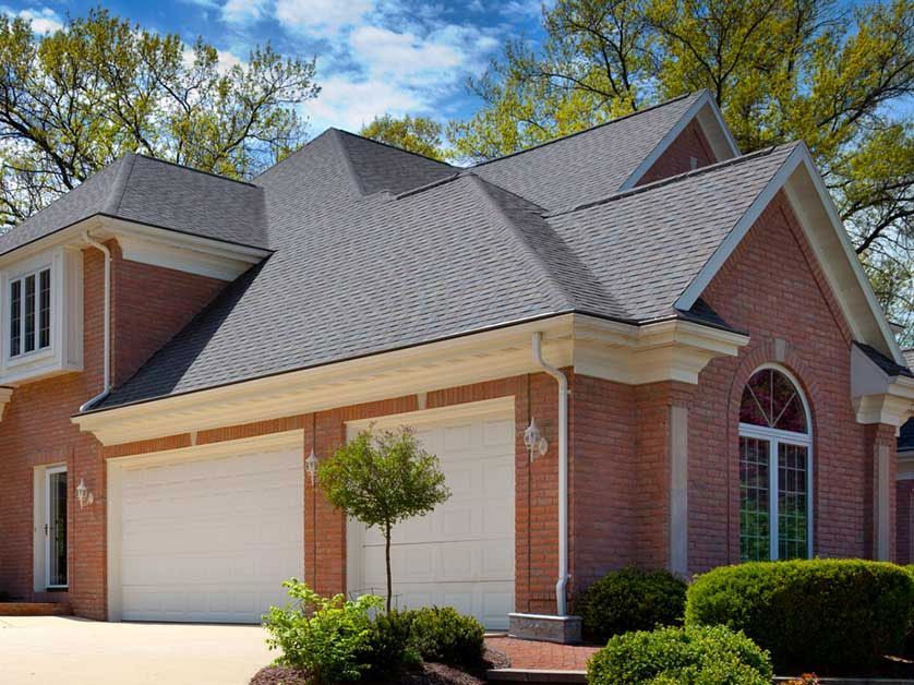 A large brick house with two garage doors and a gray roof.