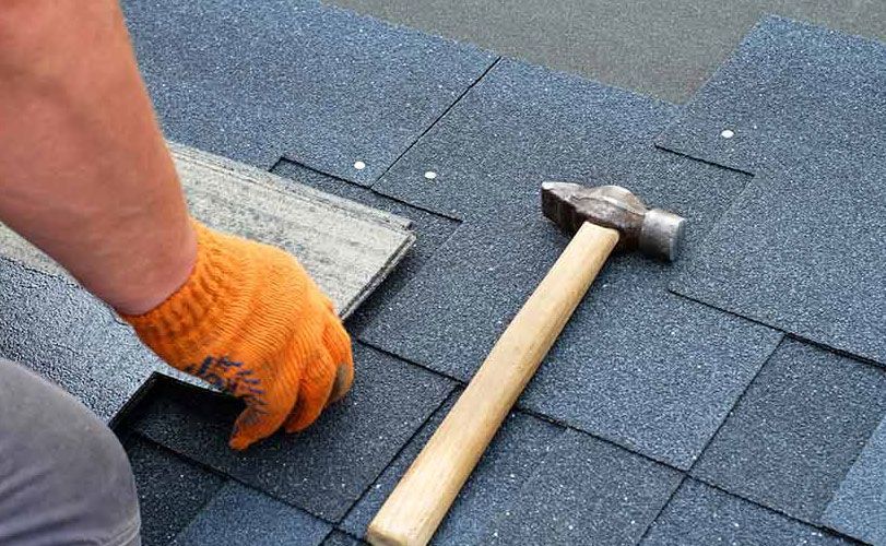 A person is using a hammer to fix a roof.
