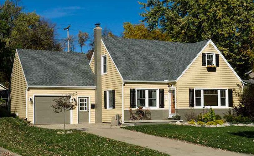 A yellow house with a gray roof and a garage