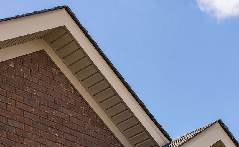 The roof of a brick house with a blue sky in the background