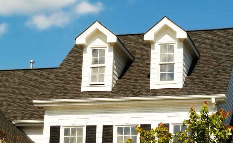 A white house with a brown roof and two dormer windows