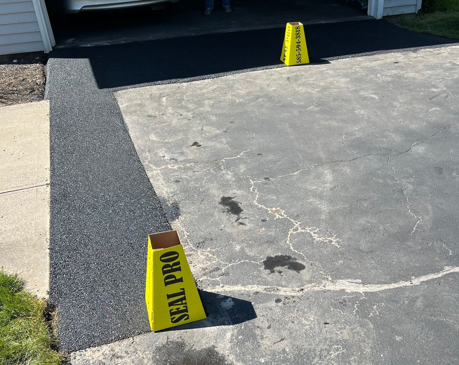 A yellow cone that says seal pro on it and repaired asphalt.