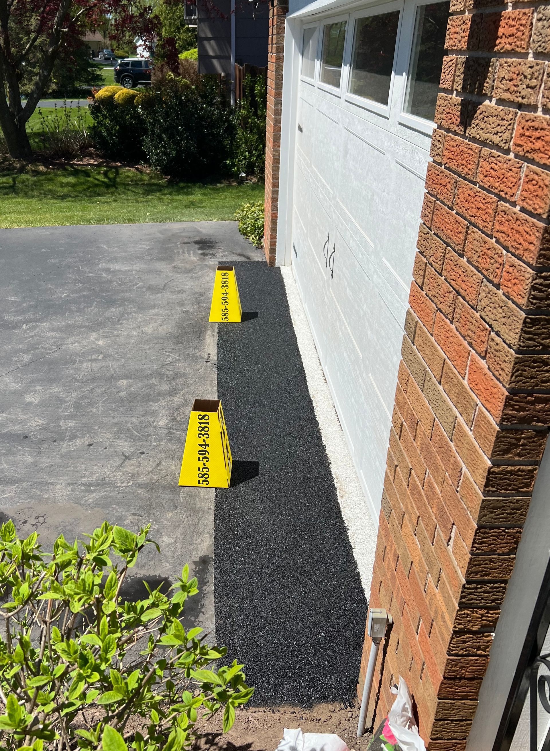 A white garage door and repaired asphalt