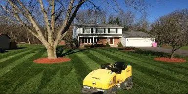 a yellow lawn mower is cutting a lush green lawn in front of a house