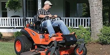 a man is riding a lawn mower in front of a house