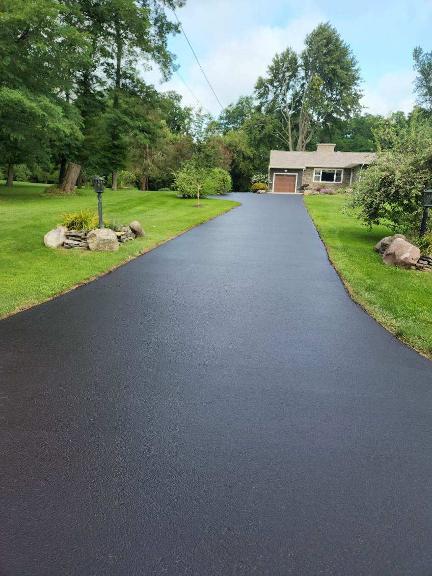 a driveway leading to a house surrounded by trees and grass