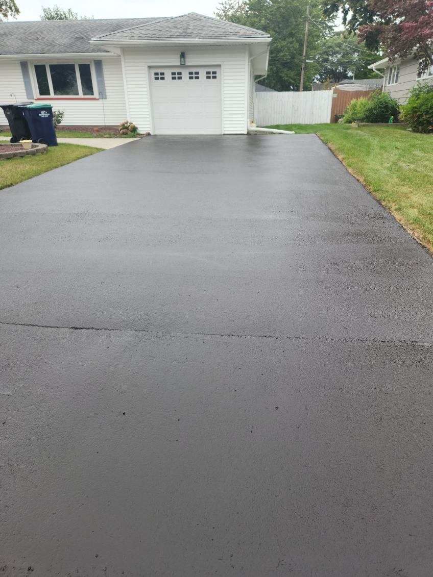 a black driveway leading to a house with a white garage door