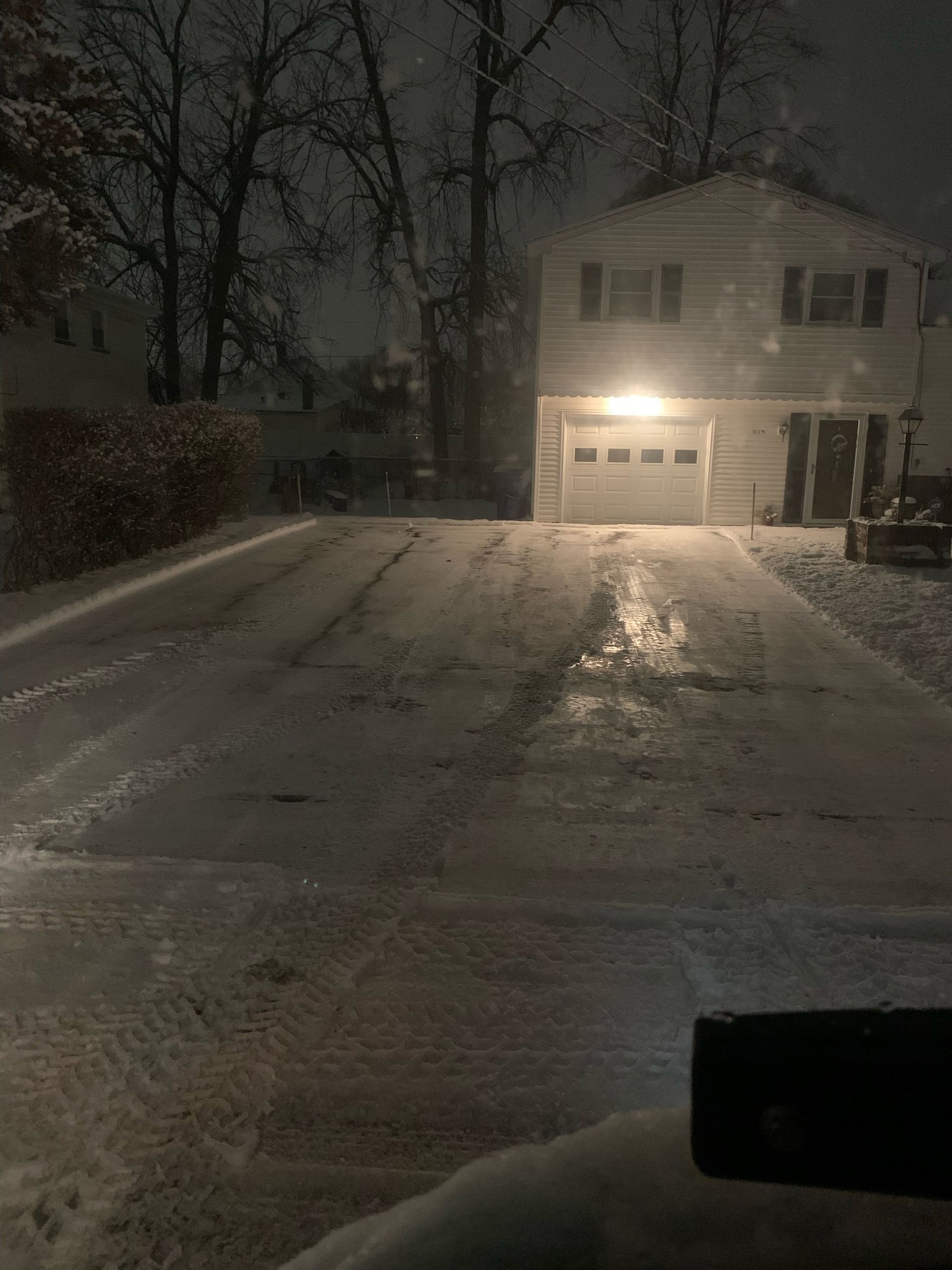a snowy driveway leading to a house at night