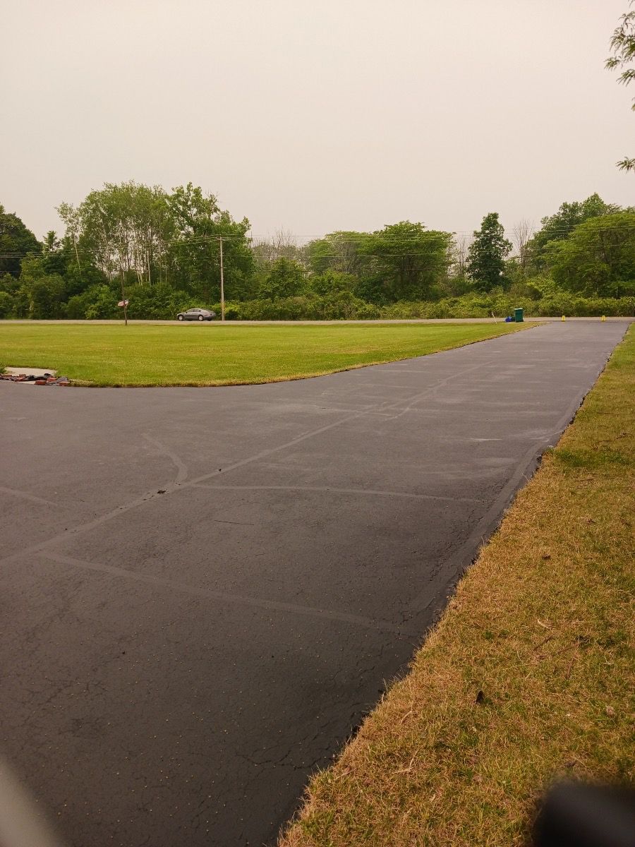 a road going through a grassy field with trees in the background